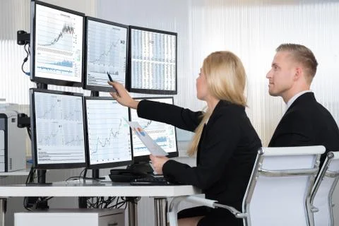 Financial workers analyzing data displayed on computer screens at desk in off Foto stock