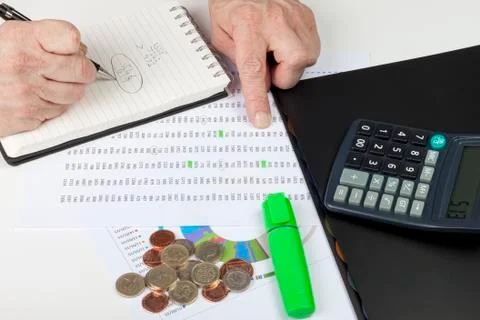 Financier referencing a spreadsheet with a calculator Foto stock