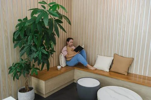 Finding information online while sitting on a bench near a plant in a remot.. Fotos Stock