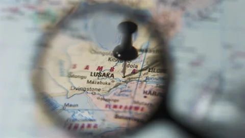Finding Lusaka on a printed map using a magnifying glass Stock Footage 339303762