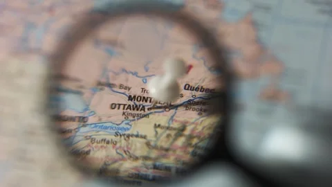 Finding Montreal on a printed map with a magnifying glass Stock Footage 339303746