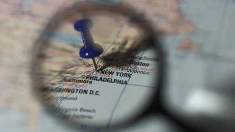 Finding New York on a printed map using a magnifying glass Stock Footage 339303744