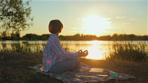Finding peace by the lake as the sun sets over the horizon Stock Footage 346721703