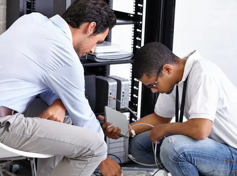 Finding the problem and correcting it. Two IT professionals working on a serv Stock Photos