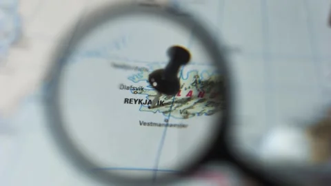 Finding Reykjavik on a printed map using a magnifying glass Stock Footage 339303761