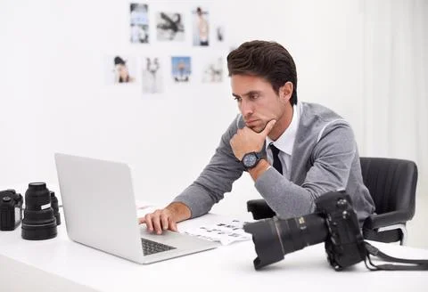 Finding the right image for his project. a young photographer sitting at his Stock Photos