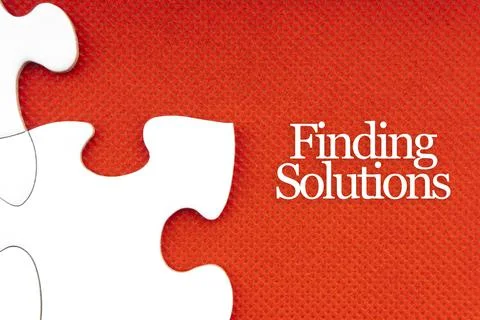 FINDING SOLUTIONS text with jigsaw puzzle on red background. 库存照片