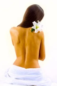 Fine back of a sunburnt brunette with the towel and white flower on her shoulder Stock Photos