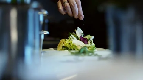 Fine dining chef elegantly finishing a dish by seasoning with salt before Vidéo 152347064