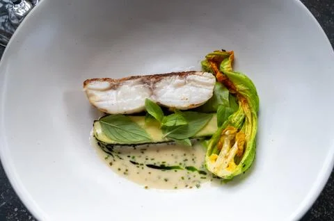 Fine dining in restaurant with chef, main  dish with white fish, young zucc.. Stock Photos