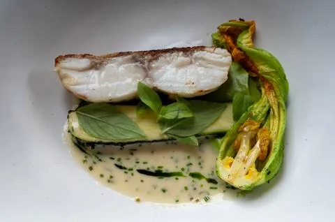 Fine dining in restaurant with chef, main  dish with white fish, young zucc.. Stock Photos