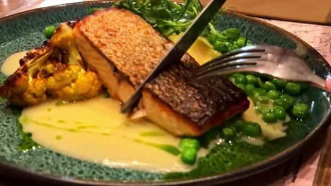 Fine dining salmon fillet cutting crispy skin peas cauliflower plate Stock Footage 341536356