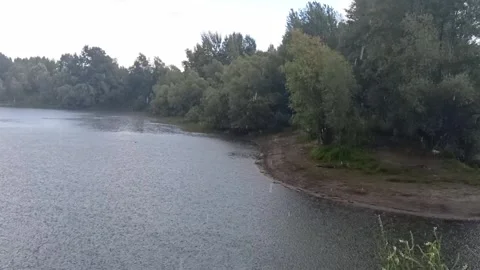 A fine but steady rain begins over the gentle bank of a narrow river Stock Footage 331519633