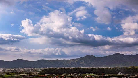 In fine weather, billowing clouds fly over the mountain and valley city. Stock Footage 278176054