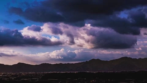 In fine weather, billowing clouds fly over the mountain and valley city. Video stock 278176070