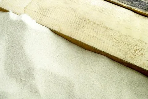 Fine white sand next to a rustic wooden plank, creating a natural textured .. Stock Photos