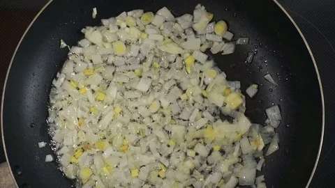 Finely chopped onion are fried in a hot frying pan. Olive or sunflower oil hi Stock Footage 76945205