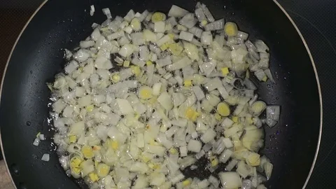 Finely chopped onions are fried in a hot frying pan. Olive or sunflower oil h Stock Footage 76945892