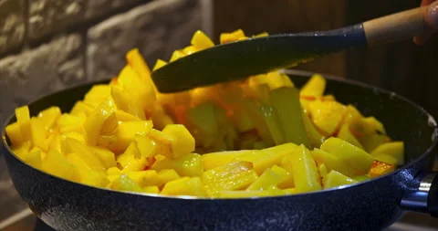 Finely chopped potatoes are fried in iron pan. Housewife stirs the potatoes with Stock Footage 237422453