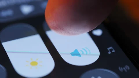 Finger adjusting Iphone smartphone volume slider on mobile device screen. Stock Footage 334023058