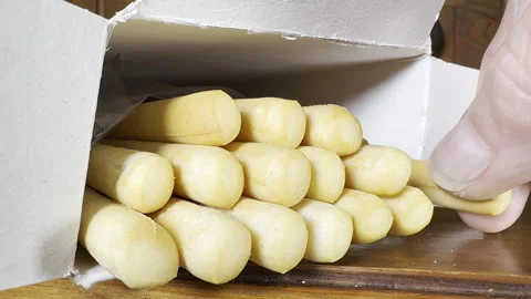 A finger and thumb slowly pulling a long, thin, crisp breadstick from a box. Video stock 299983793
