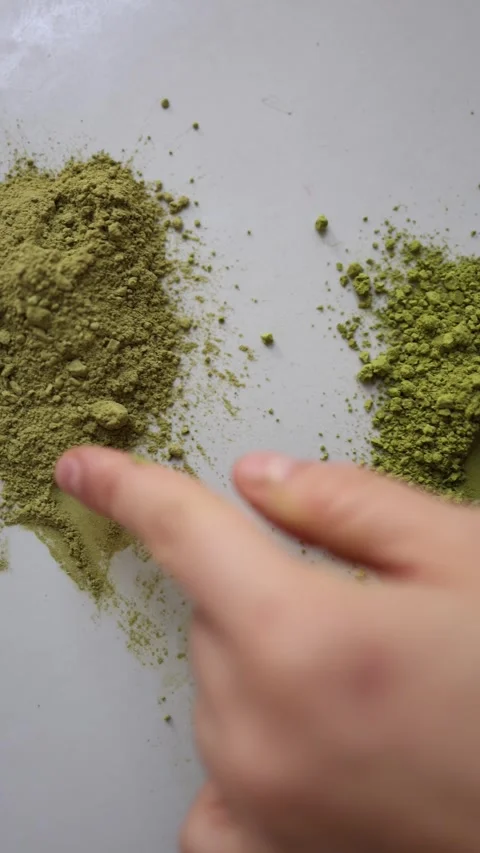 Finger compares two matcha powders by color texture and consistency Video stock 342610696