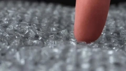 Finger compresses ruptures bubbles on air wrap film plastic packaging material Stock-Footage 131619778