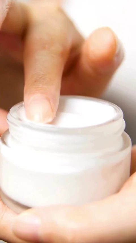Finger dips into white moisturizing cream in small jar Stock Footage 331933525