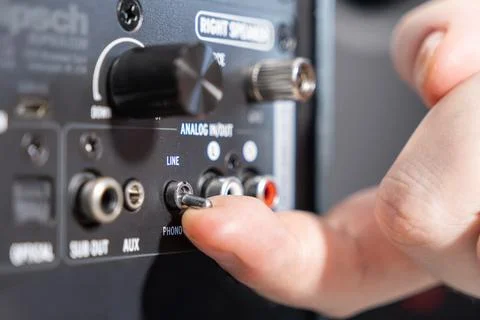 A finger flipping a small toggle switch on the back panel of a speaker to Stock Photos
