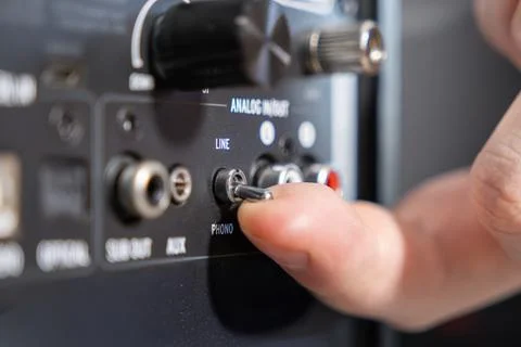 A finger flipping a toggle switch on an audio amplifier rear panel, adjusting Stock Photos