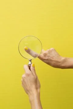 Finger of a hand viewed through a magnifying glass Stock Photos