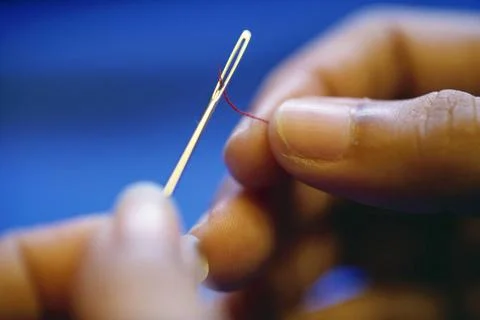 Finger inserting thread in needle Copyright: xVxMishra/DinodiaxPhotox  Foto stock