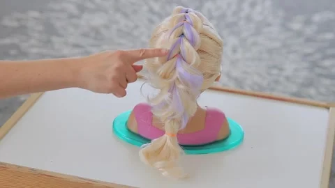Finger moving down dragon braid on blonde mannequin head Stock Footage 331997398