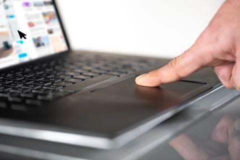 Finger moving mouse pointer on laptop touchpad, profile view Stock Photos