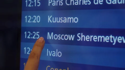 Finger pointing at flight schedule display showing departure times for Video stock 328480981