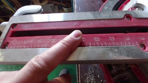 Finger pointing at the red measurement scale on a miter saw in a workshop Stock Footage 335644444