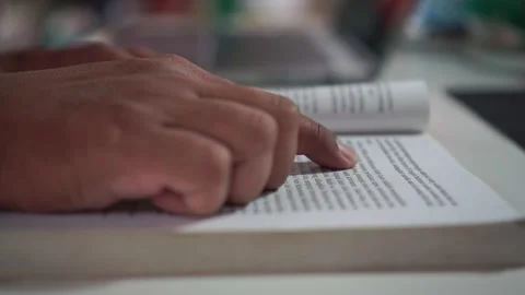 Finger pointing at text while reading an open book. Stock Footage 347686242
