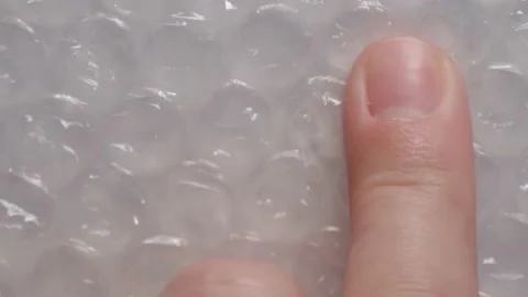 Finger pops a bubble by tapping on wrapping film of plastic packaging material Video stock 154825956
