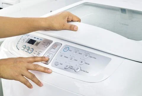 Finger press button start on white washing machine 库存照片