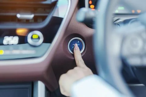 Finger press a car ignition button or START engine inside modern electric a.. Stock Photos