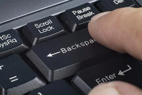 Finger presses backspace key on computer keyboard Stock Photos