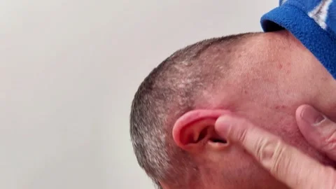 Finger Presses Behind Ear Highlighting Anatomy and Discomfort Gesture Video stock 329213564