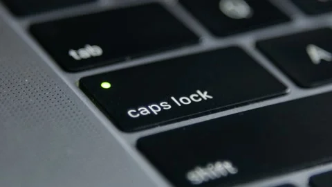 Finger presses the Caps Lock Button on laptop keyboard once and several times Stock Footage 168966443