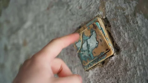 A finger presses a non-working light switch on a clay wall in the village Stock Footage 199742981