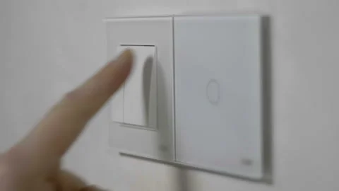 A finger presses one of the three white switches on the wall Stock Footage 130070544