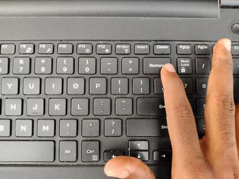 Finger pressing a backspace button on the laptop keyboard. Selective focus Stock Photos