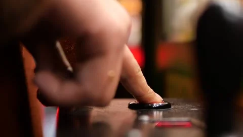 Finger pressing button on arcade machine in game room Stock Footage 332688742