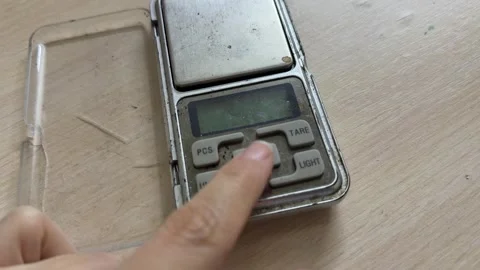 Finger pressing button on digital pocket scale with blue display, weight Stock Footage 337121615