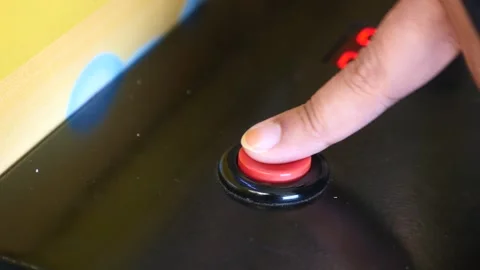 Finger pressing a button on a gaming machine in an arcade Stock Footage 321265114