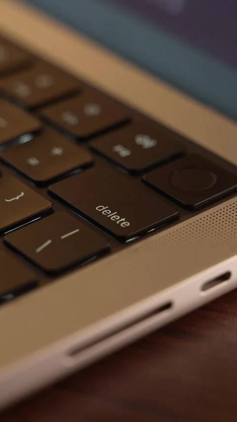 Finger Pressing the Delete Button on a Laptop Keyboard in a Warm Lighted Room. Stock Footage 340967834